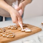 A person decorating festive Christmas cookies with icing, enhancing holiday spirit.
