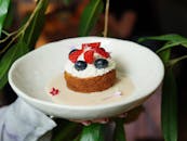 Appetizing homemade cheesecake topped with strawberries and blueberries, held in a bowl.