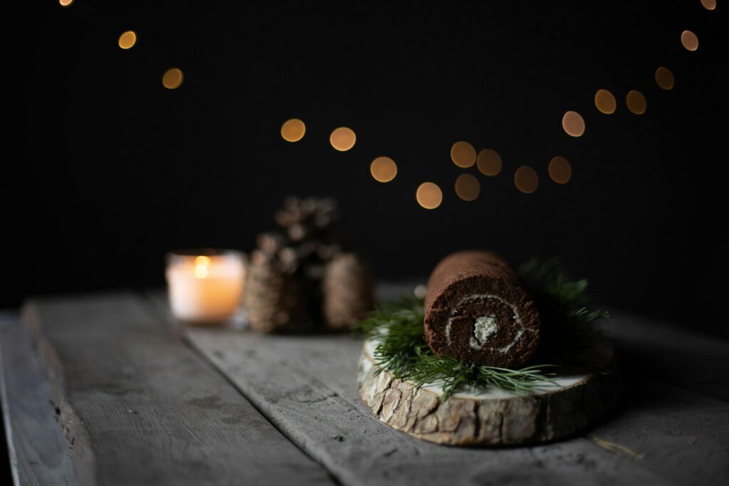 Chocolate cake roll on a rustic board with bokeh lights, ideal for holiday themes.